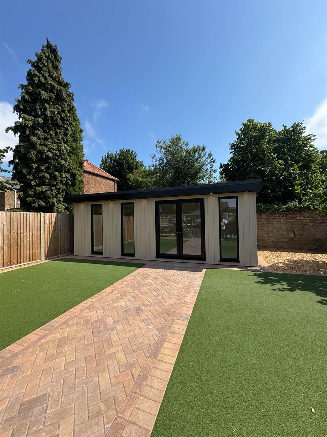 Completed garden room viewed along a herringbone block-paved path